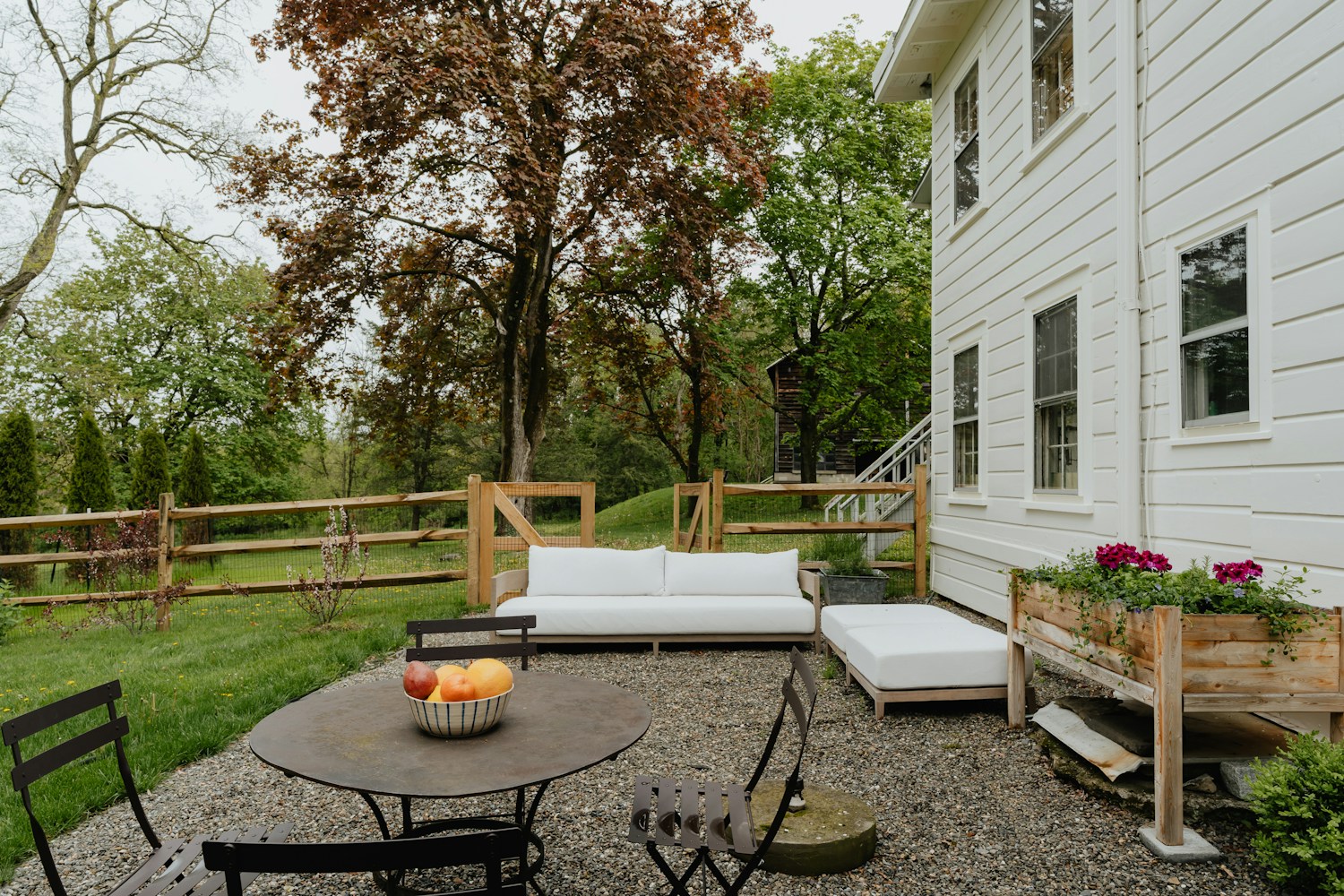 A gravel dining terrace with outdoor seating, planting and a garden view